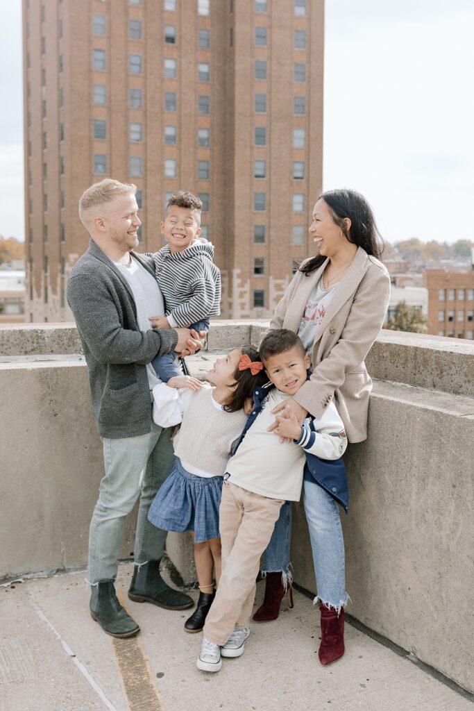 A family with three children poses on a rooftop in downtown Aurora, Illinois for their family photos taken by Charity White Photography