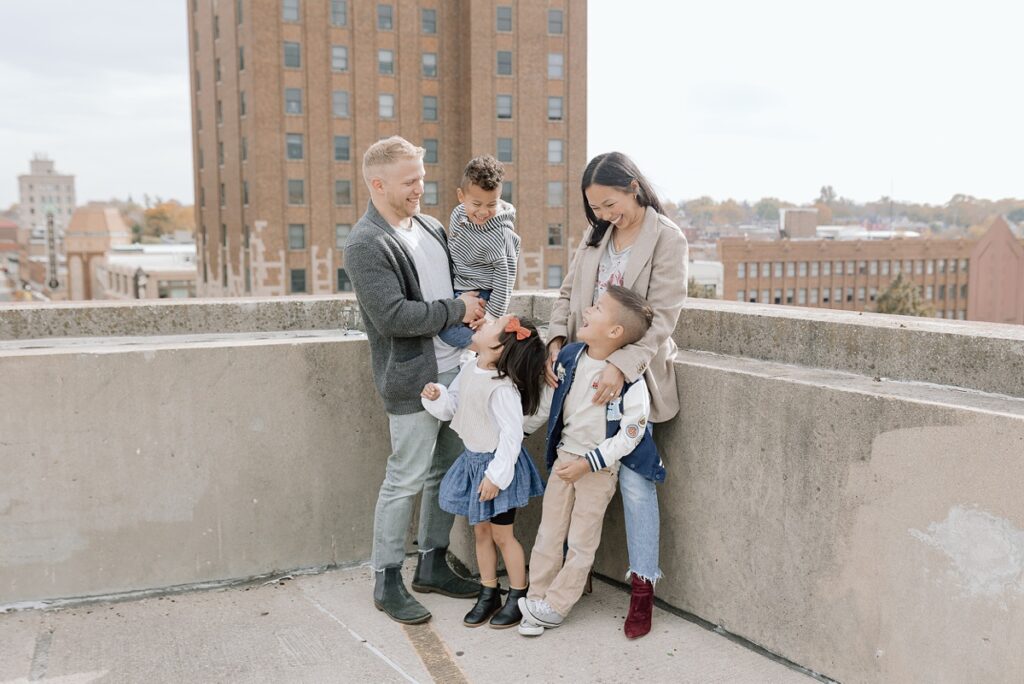 A family with three children poses on a rooftop in downtown Aurora, Illinois for their family photos taken by Charity White Photography