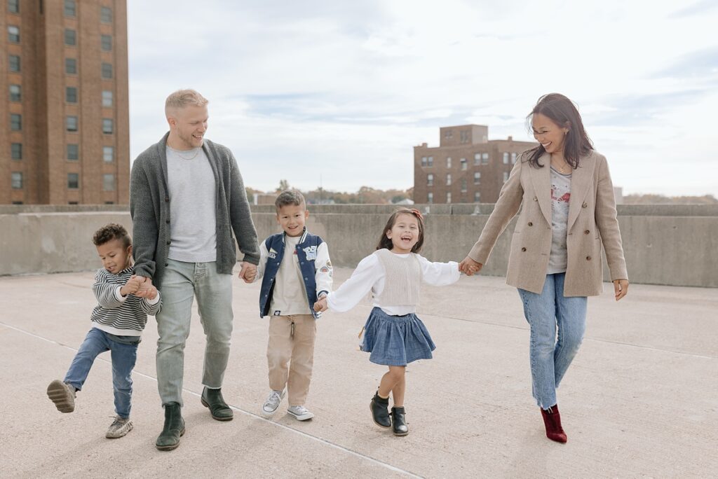 A family with three children poses on a rooftop in downtown Aurora, Illinois for their urban family photos taken by Charity White Photography