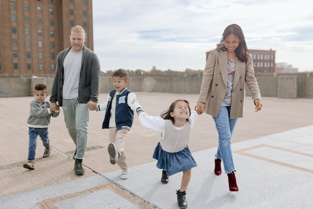 A family with three children poses on a rooftop in downtown Aurora, Illinois for their urban family photos taken by Charity White Photography