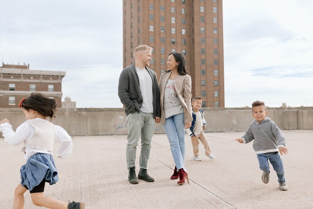 A family with three children poses on a rooftop in downtown Aurora, Illinois for their urban family photos taken by Charity White Photography