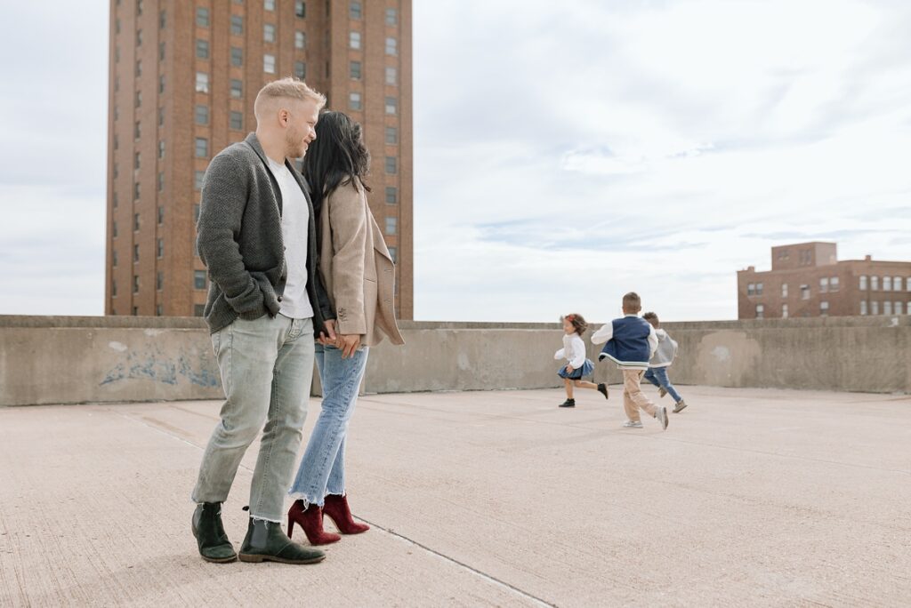 A family with three children poses on a rooftop in downtown Aurora, Illinois for their urban family photos taken by Charity White Photography