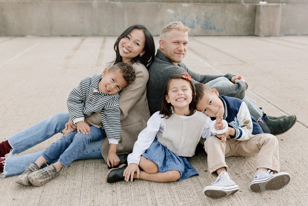 A family with three children poses on a rooftop in downtown Aurora, Illinois for their urban family photos taken by Charity White Photography