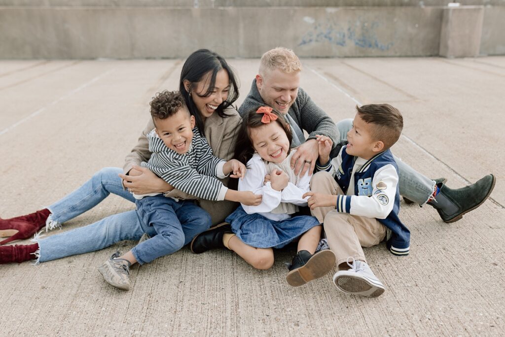 A family with three children poses on a rooftop in downtown Aurora, Illinois for their urban family photos taken by Charity White Photography