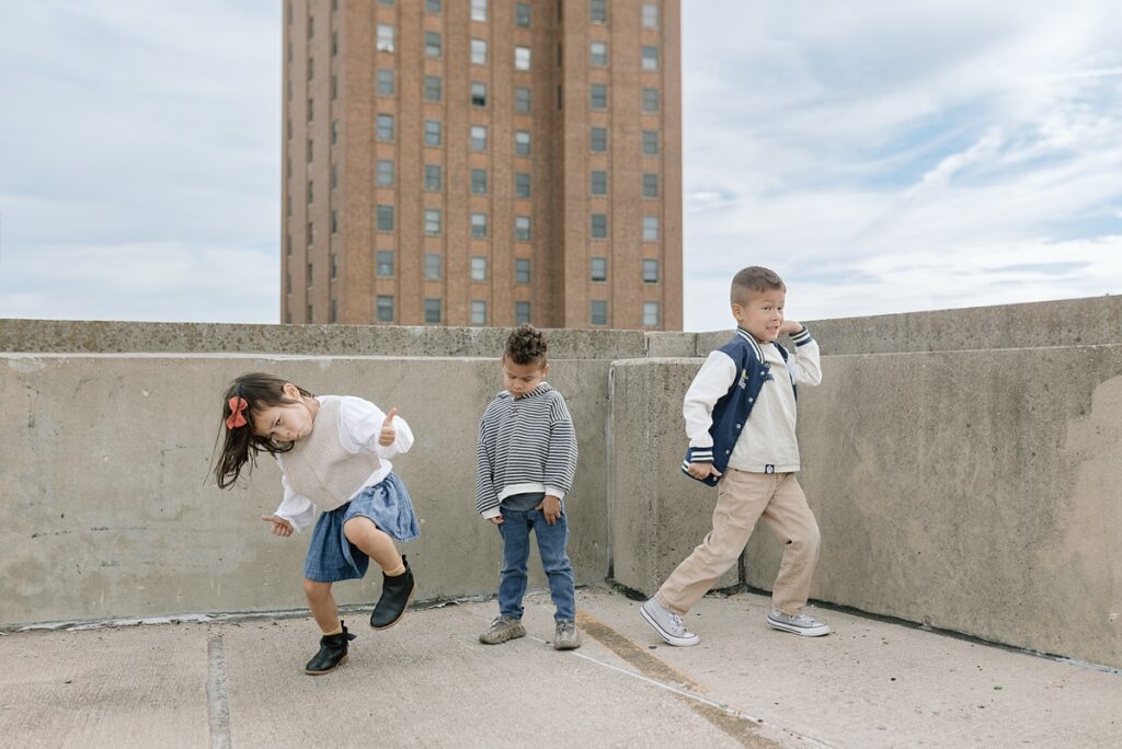 Three children pose for their family photos in downtown Aurora Illinois on a parking garage rooftop