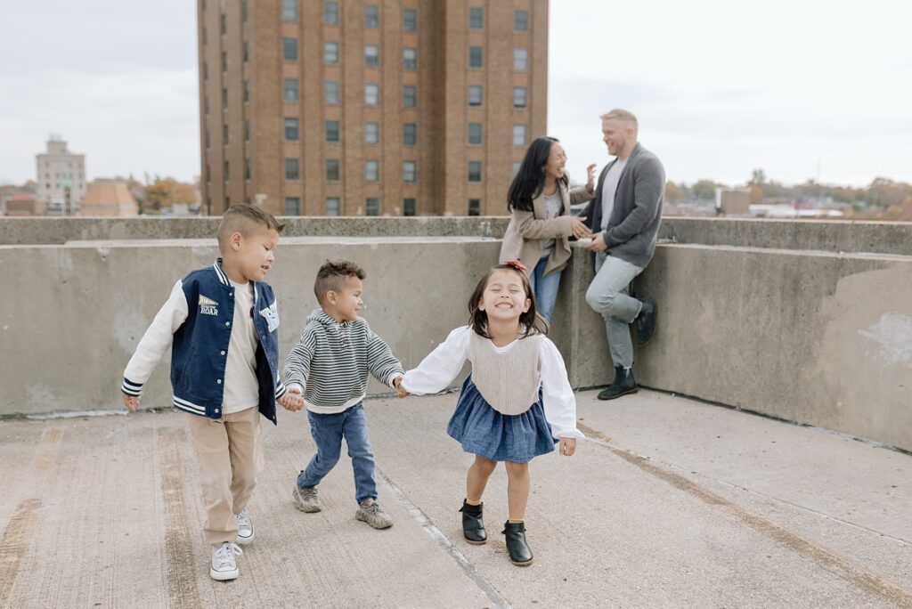 A family with three children poses on a rooftop in downtown Aurora, Illinois for their family photos taken by Charity White Photography