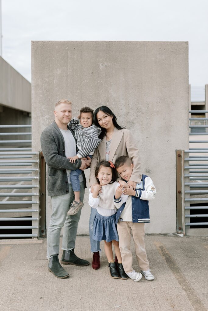 A family with three children poses on a rooftop in downtown Aurora, Illinois for their urban family photos taken by Charity White Photography