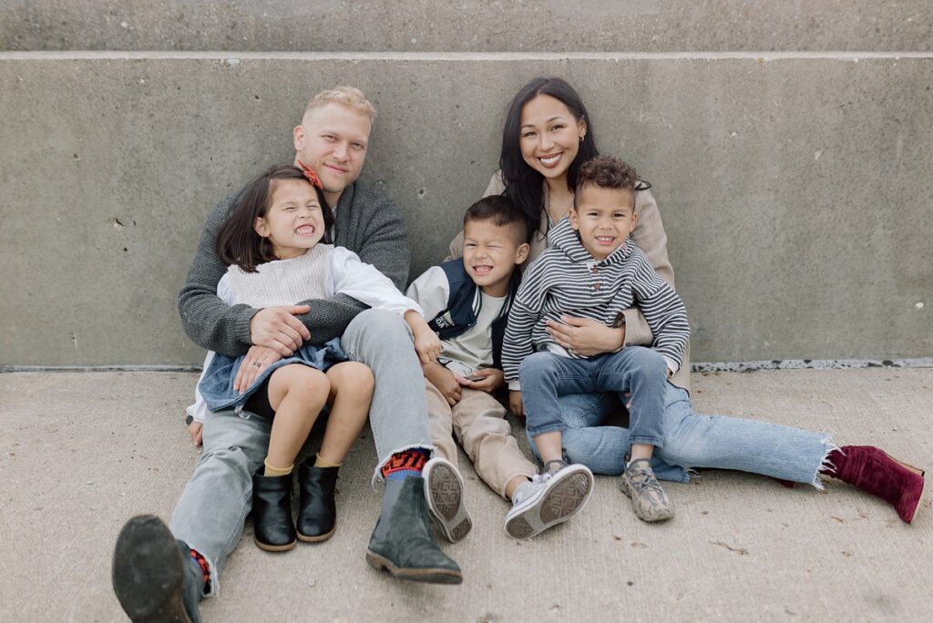 A family with three children poses on a rooftop in downtown Aurora, Illinois for their urban family photos taken by Charity White Photography