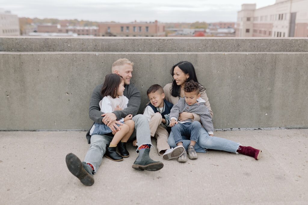 A family with three children poses on a rooftop in downtown Aurora, Illinois for their urban family photos taken by Charity White Photography