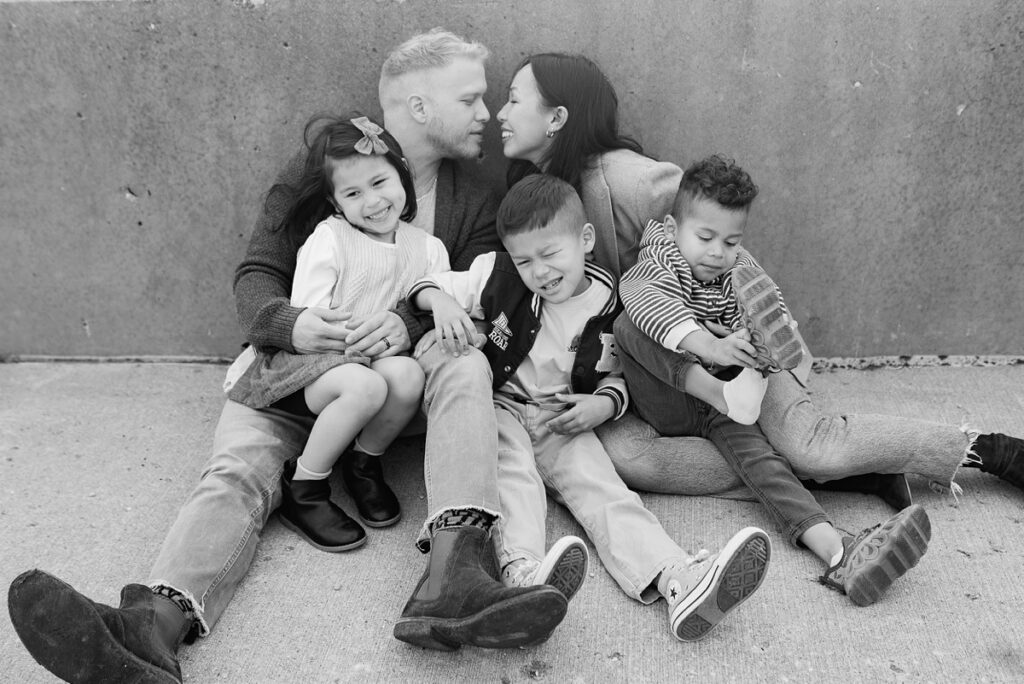 A family with three children poses on a rooftop in downtown Aurora, Illinois for their urban family photos taken by Charity White Photography