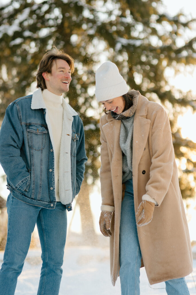 A young married couple runs and laughs and hugs in the snow. Wintery couples photoshoot in Lombard Illinois.