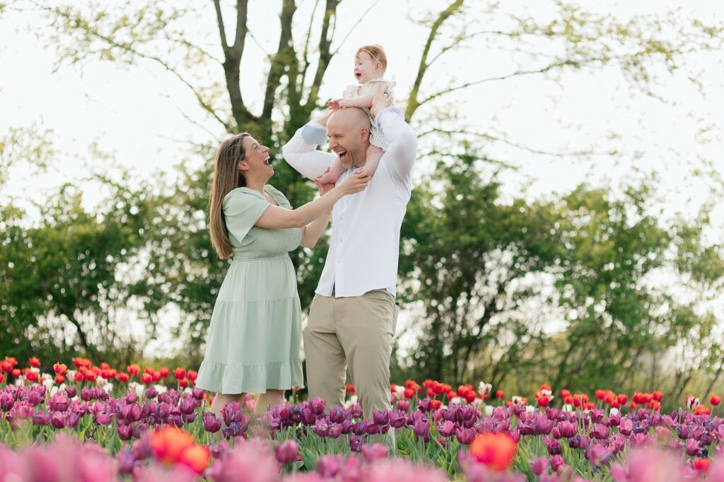 Family of three laughing and interacting together while surrounded by tulips.